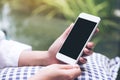 A woman`s hand holding white smart phone with blank black desktop screen with blur green nature background Royalty Free Stock Photo