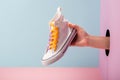 Woman`s hand holding a white sneaker on blue and pink background Royalty Free Stock Photo