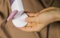 A woman`s hand holds a bottle of micellar water, a tonic cosmetic product with a cotton pad on a beige background