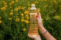 A woman's hand holds a bottle of rapeseed oil