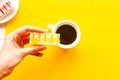 Woman`s hand holds a cake over bright yellow background Royalty Free Stock Photo