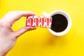 Woman`s hand holds a cake over bright yellow background Royalty Free Stock Photo