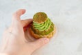 A woman`s hand holds a cake with pistachio cream, a place for text Royalty Free Stock Photo