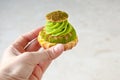 A woman`s hand holds a cake with pistachio cream, a place for text Royalty Free Stock Photo