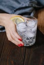 The woman`s hand holds the cocktail with club soda, vodka, lemon and ice on a wooden table Royalty Free Stock Photo