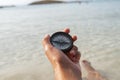 A woman`s hand holds a compass in the sea