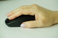 Caucasian Woman using a black wireless computer mouse on white background. A woman's hand holds a computer mouse. Working th Royalty Free Stock Photo