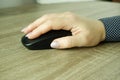 Woman using black wireless computer mouse on wooden background. A woman's hand holds a computer mouse. Working with th Royalty Free Stock Photo