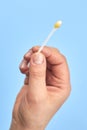 A woman`s hand holds a cotton swab with earwax