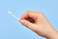 A woman`s hand holds a cotton swab with earwax