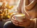 A woman\'s hand holds a cup of coffee in her palm