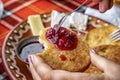 Hand holds a fried slice of bread with jam at breakfast