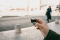 A woman`s hand holds a glass made of chocolate in which traditional Portuguese liqueur is tinted named Ginjinha and