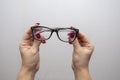 A woman`s hand holds glasses, selection of glasses to improve vision on a gray background, recommendations of ophthalmologists