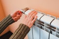 A woman& x27;s hand holds the heating thermostat handle. Heating service cost concept, utility price increase