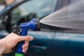 A woman`s hand holds a hose for washing the car. Water, spray, jet. The idea is to wash your car in front of your house Royalty Free Stock Photo