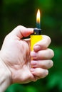 A woman`s hand holds a lighter with a burning flame outside on the street. A burning lighter in a woman`s hand.. Royalty Free Stock Photo