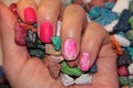 A woman`s hand holds a pile of colored candies. Chocolate in the form of bright stones. Pink manicure