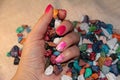 A woman`s hand holds a pile of colored candies. Chocolate in the form of bright stones. Pink manicure