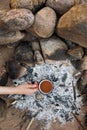 a woman& x27;s hand holds a red cup of coffee or tea against the background of a campfire on a hike. hiking and outdoor Royalty Free Stock Photo