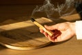 woman's hand holds a smoking stick of the sacred palo santo tree.