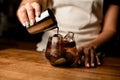 woman& x27;s hand holds steel cup and pours coffee into bowl with cold herbal drink Royalty Free Stock Photo