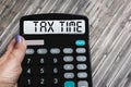 A woman\'s hand holds the word Tax time on a calculator. Business and taxation concept Royalty Free Stock Photo