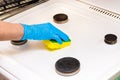 Woman`s hand in a household glove sponges a gas stove. Cleaning the kitchen and washing the burners Royalty Free Stock Photo