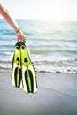 WomanÃÂ´s hand keep snorkel and swimming fins on a sandy beach. Water sports. Snorkeling. Travel and holiday concept. Royalty Free Stock Photo