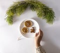 Woman`s hand in a knitted sweater holds a plate of Christmas sweets. Cookies in the form of a man in a mask and dried Royalty Free Stock Photo