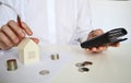 Layout of a house made of white paper and a woman& x27;s hand, a calculator on a white table. The concept of a mortgage. Royalty Free Stock Photo