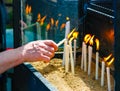 Woman`s hand lighting candle in pedestal of church. Close-up shoot Royalty Free Stock Photo