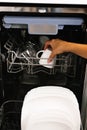 Woman`s hand loading dishes, emptying or unloading them from an open automatic built-in dishwasher with dishes inside in the kitc Royalty Free Stock Photo