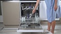 A woman's hand loads a dishwasher with dirty dishes