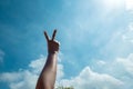 A woman`s hand making a peace sign with two fingers in front of the sky Royalty Free Stock Photo