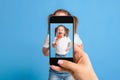 Woman`s hand making photo of a little girl with a mobile phone. Selective focus on a mobile phone with a portrait of a Royalty Free Stock Photo