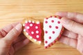 Woman's hand and man's hand holding two half heart shaped cookies attach on wooden background Royalty Free Stock Photo