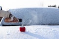 A woman`s hand in a mitten pours boiling water into a mug from a thermos on a snow-covered hood of a car on a bright winter sunny