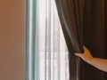 Woman`s hand opening brown luxurous curtain