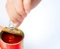 Woman`s hand opens lid of canned fish on white background. Sardine in tomato sauce. Processed food. Canned fish in tin can. Royalty Free Stock Photo