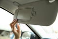 Woman`s hand opens the sun visor in the car.