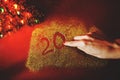 The woman`s hand paint the figure of 2020 in the claret background with sparkles. New Year`s concept Royalty Free Stock Photo