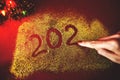 The woman`s hand paint the figure of 2020 in the claret background with sparkles. New Year`s concept Royalty Free Stock Photo