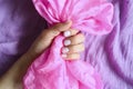 A woman`s hand with pale lilac nails holds a pink silk fabric against a background of lilac cotton fabric Royalty Free Stock Photo