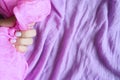 A woman`s hand with pale lilac nails holds a pink silk fabric against a background of lilac cotton fabric Royalty Free Stock Photo