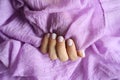 A woman`s hand with pale lilac nails and lilac cotton fabric Royalty Free Stock Photo