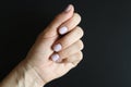 Woman`s hand with pale lilac painted nails on a black background