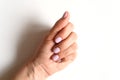 Woman`s hand with pale lilac painted nails on a white background