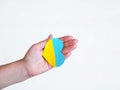 A woman's hand in the palm lies a heart in the color of the Ukrainian flag of yellow and blue.