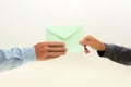 Woman's hand passes envelope to male hand on white